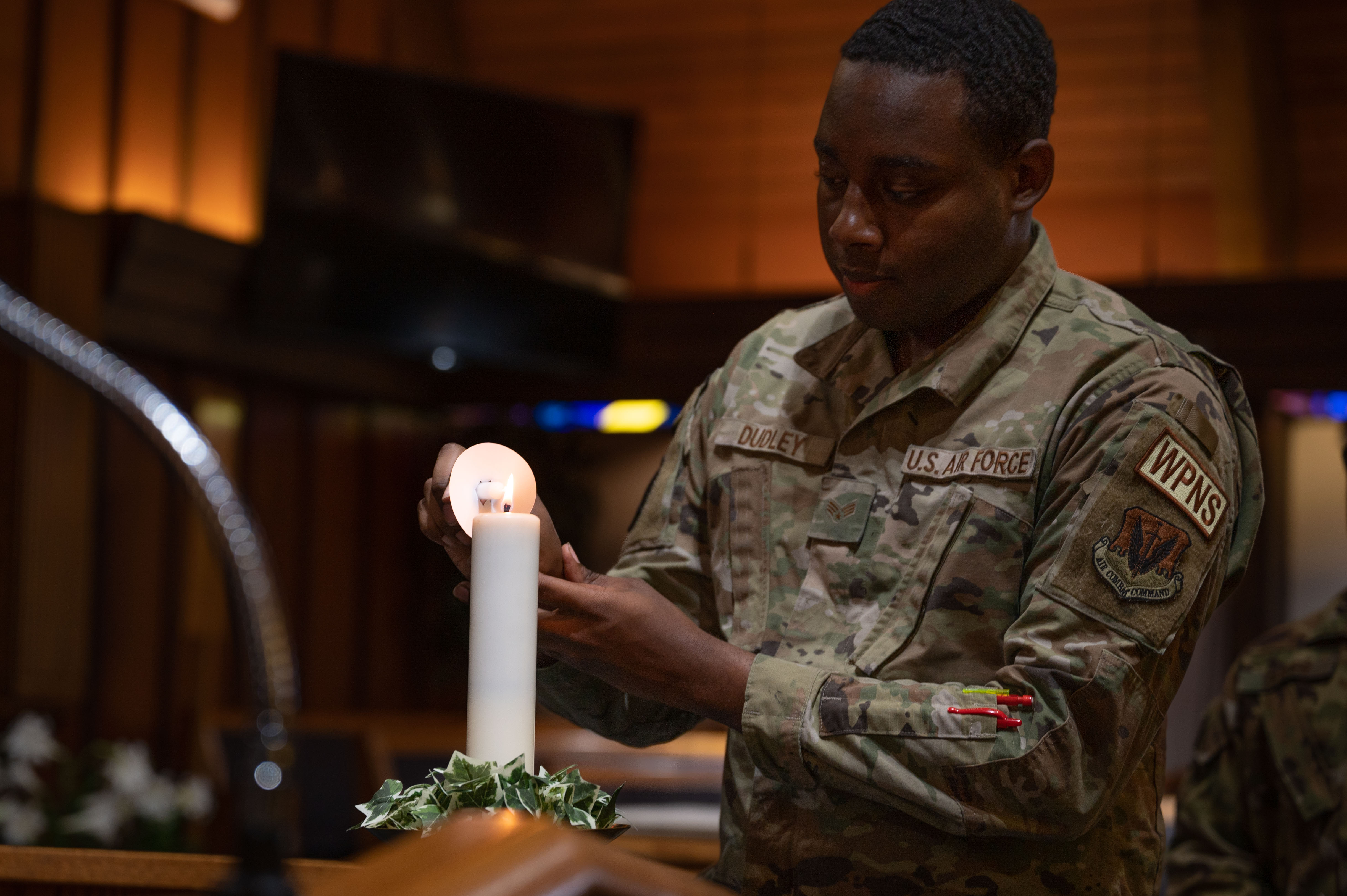 U.S. Air Force Senior Airman Azhmere Dudley, 57th Aircraft Maintenance Squadron weapons load crew member, lights a candle during a Holocaust Remembrance candle vigil at Nellis Air Force Base, Nevada, April 18, 2023. During the ceremony, candles were lit in honor of the victims of the Holocaust. (U.S. Air Force photo by Airman 1st Class Jordan McCoy)