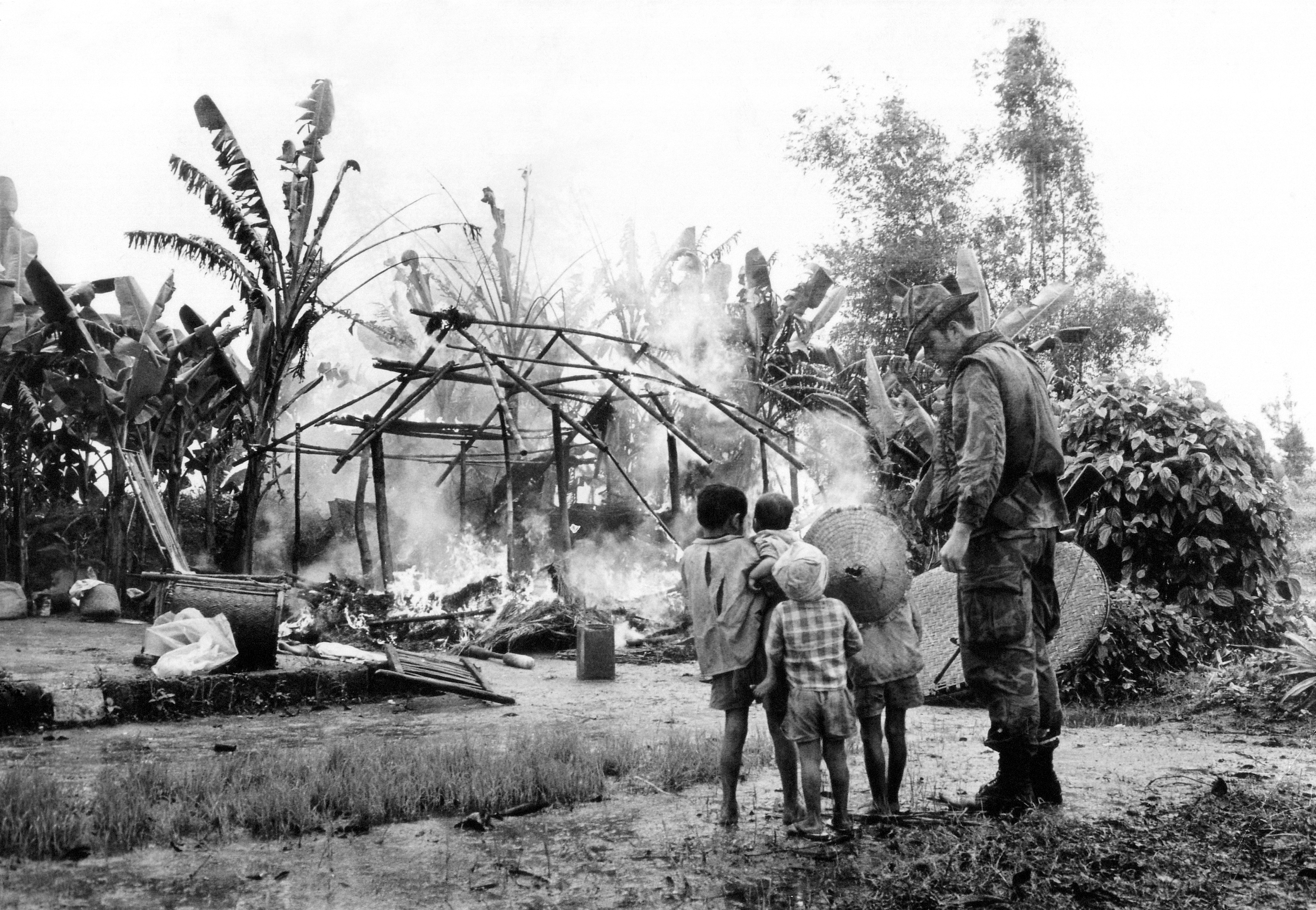 U.S. Marine stands with Vietnamese children as they watch their house burn after an Allied patrol set it ablaze after finding communist AK-47 ammunition, Jan. 13, 1971. Patrol made up of U.S. Marines and South Vietnamese popular forces searched the village, 25 miles south of Da Nang. (AP Photo/HJ)