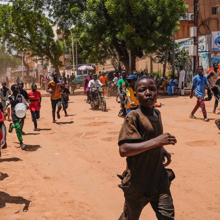 Children run in the streets of Niamey, Niger, Sunday, Aug. 13, 2023. People marched, biked and drove through downtown Niamey, chanting "down with France" and expressing anger at ECOWAS. (AP Photo/Sam Mednick)