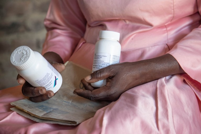 A woman holds her HIV medication and a hospital records book at her home in Harare, Zimbabwe, Friday, Feb. 7, 2025.