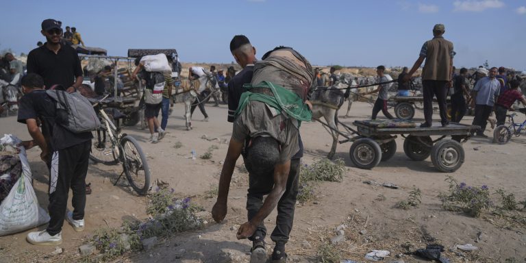 A Palestinian carries the body of a man killed while trying to receive aid near a distribution center operated by the U.S.-backed Gaza Humanitarian Foundation (GHF) in Netzarim, in the Gaza Strip, Monday, Aug. 4, 2025.