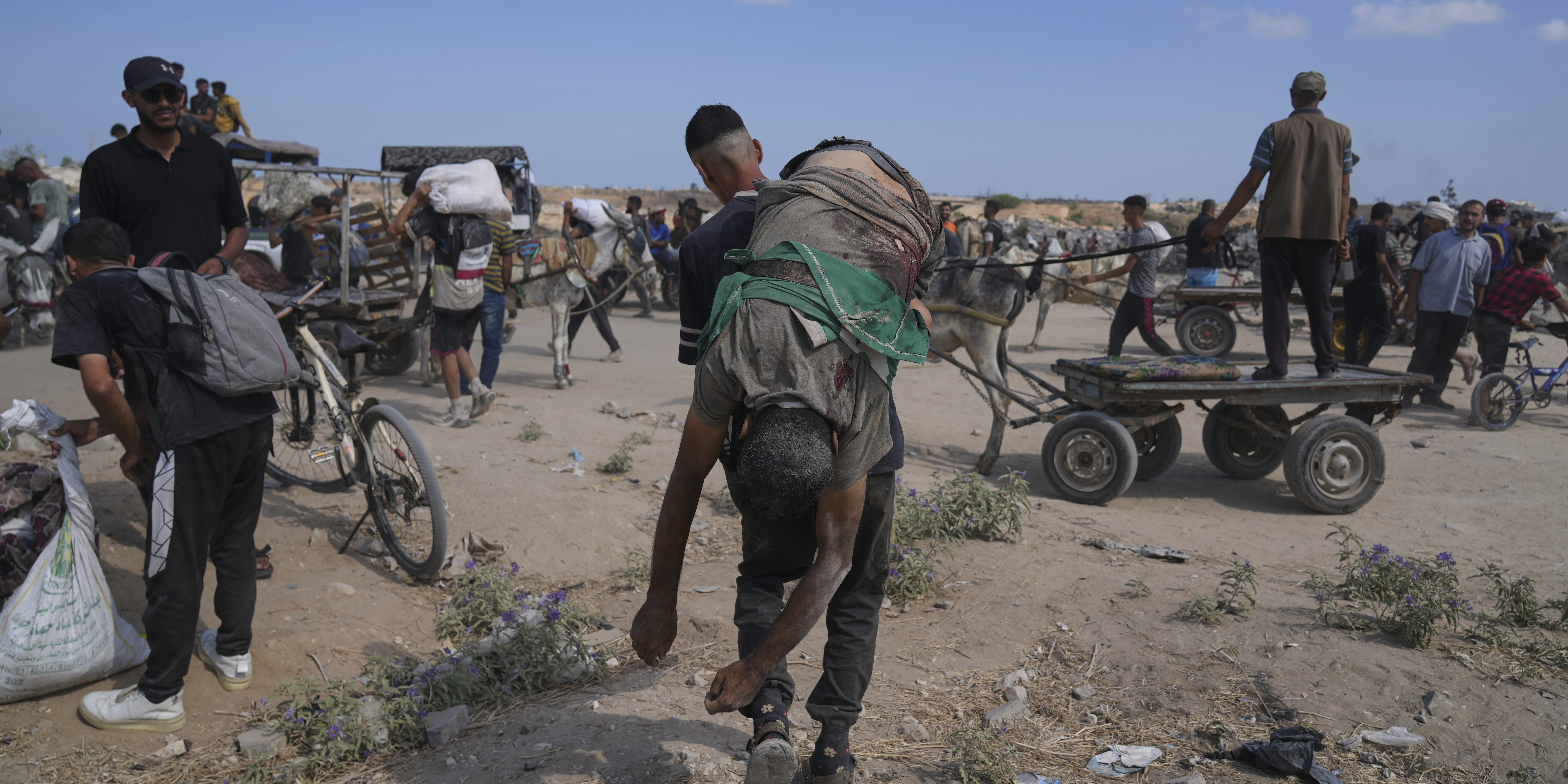 A Palestinian carries the body of a man killed while trying to receive aid near a distribution center operated by the U.S.-backed Gaza Humanitarian Foundation (GHF) in Netzarim, in the Gaza Strip, Monday, Aug. 4, 2025.