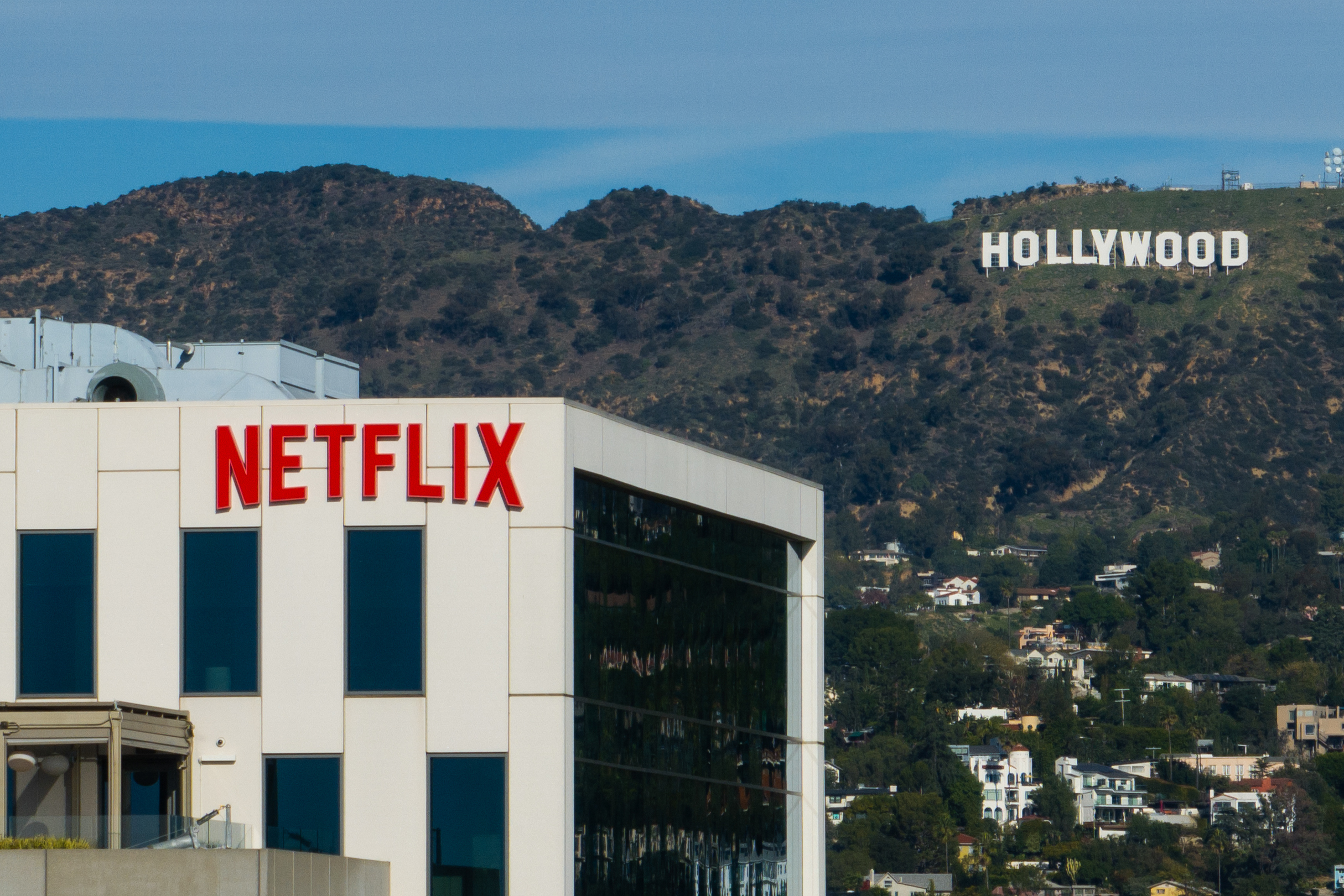 A Netflix sign atop a building in Los Angeles, Thursday, Dec. 18, 2025, with the Hollywood sign in the distance.