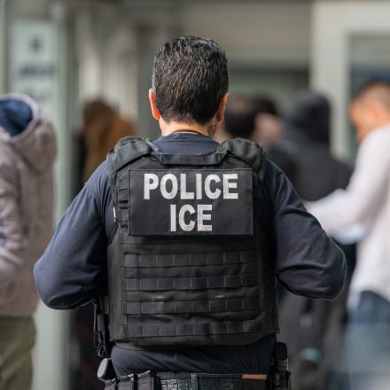An ICE agent monitors hundreds of asylum seekers being processed upon entering the Jacob K. Javits Federal Building on June 6, 2023 in New York City.