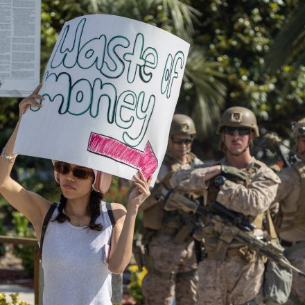 LOS ANGELES, CALIFORNIA - JUNE 12: A protester holds a sign near Marines from the Marine Corps Air Ground Combat Center (MCAGCC) at Twentynine Palms, California as they guard the Wilshire Federal Building as Vice President JD Vance visits on June 12, 2025 in Los Angeles, California. Daily protests escalated after President Donald Trump authorized military forces to protect federal property against the wishes of city and state officials. A federal appeals court ruling yesterday allows for President Trump's ongoing deployment of around 4,000 National Guard members in Los Angeles which continues to see widespread immigration raids. (Photo by David McNew/Getty Images)
