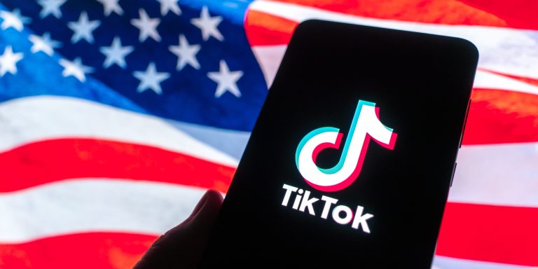 GUANGZHOU, CHINA - DECEMBER 19: In this photo illustration, the logo of TikTok is displayed on a smartphone screen with a US national flag in the background on December 19, 2025 in Guangzhou, Guangdong Province of China. TikTok's Chinese owner ByteDance has signed binding agreements with US and global investors to operate its business in America, TikTok's boss told employees on December 18. (Photo by Qin Zihang/VCG via Getty Images)