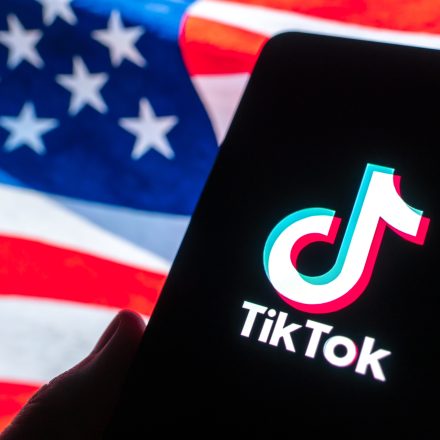 GUANGZHOU, CHINA - DECEMBER 19: In this photo illustration, the logo of TikTok is displayed on a smartphone screen with a US national flag in the background on December 19, 2025 in Guangzhou, Guangdong Province of China. TikTok's Chinese owner ByteDance has signed binding agreements with US and global investors to operate its business in America, TikTok's boss told employees on December 18. (Photo by Qin Zihang/VCG via Getty Images)