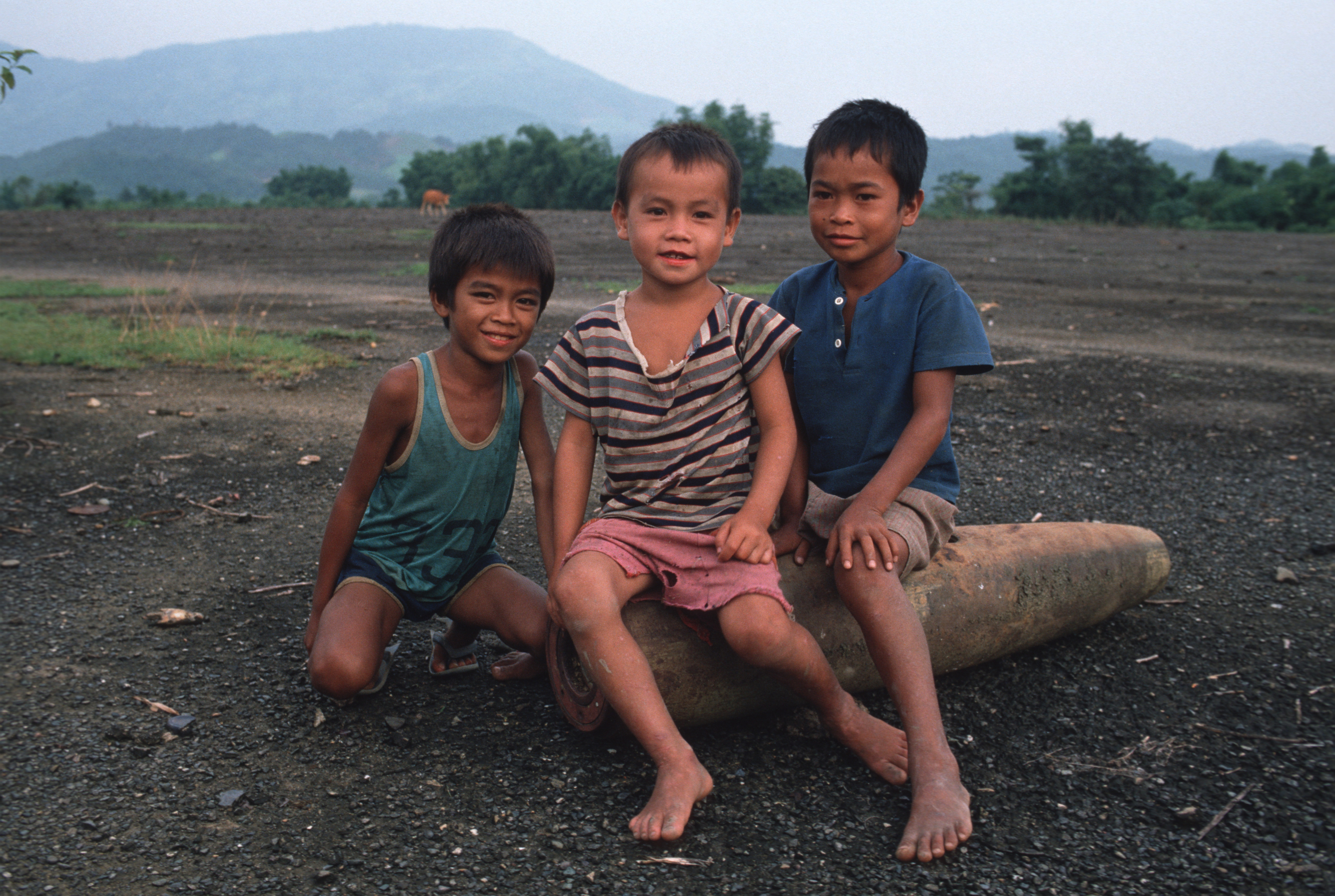 VANG VIENG, LAOS - 1989/09/01: Kids in Vang Vieng playing with a disarmed American bomb dropped during the Vietnam War. Over 100 people die each year from UXO, unexploded ordnance. (Photo by Gerhard Joren/LightRocket via Getty Images)